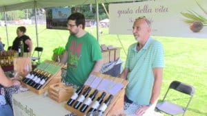 two men talking about olive oil from gusto della vita at a festival's vendor table in new york