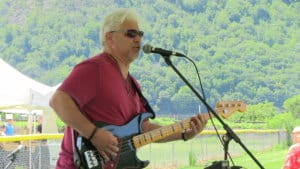 a musician singing into a mic while playing electric guitar outside