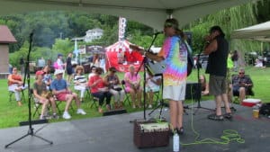 musicians on a stage with people in the background enjoying food wine and music at a festival